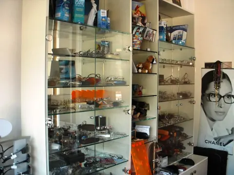 Staklene vitrine sa naočarima, kutijama kontaktnih sočiva i promotivnim posterom